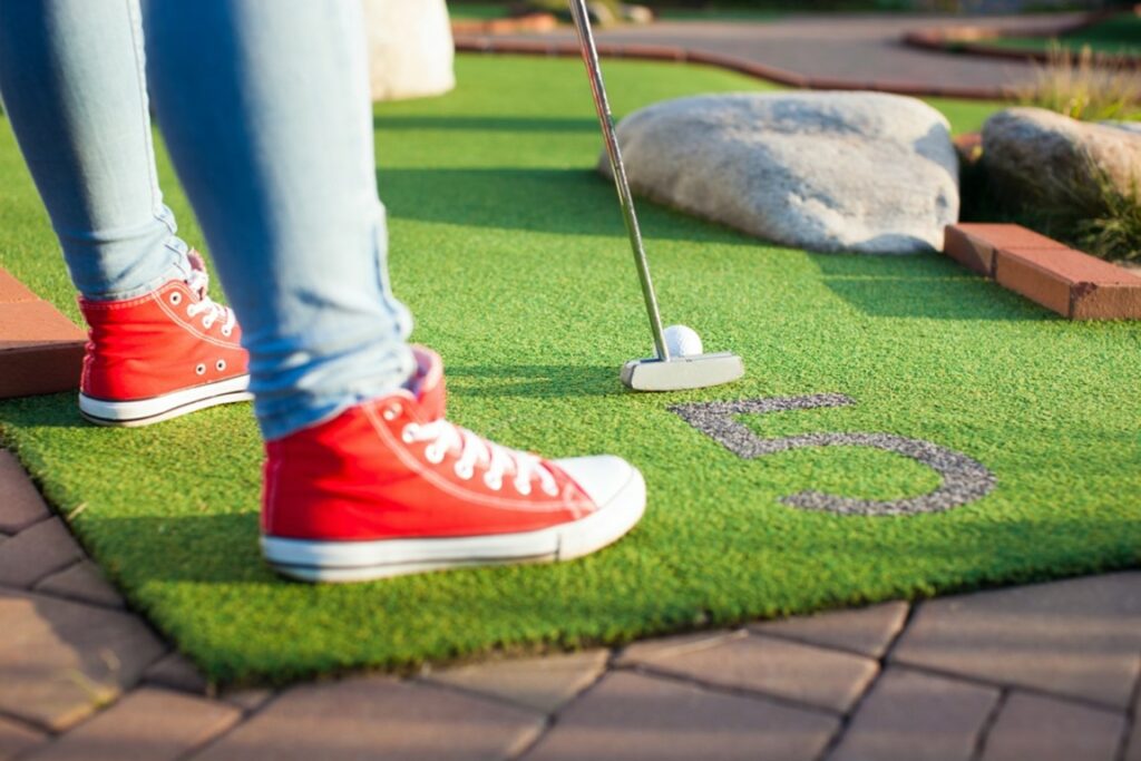 Cropped view of a kid playing mini golf.
