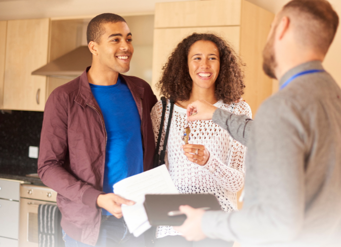 Letting agent giving keys to a happy couple.