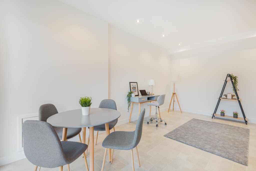 Wide and light room with dining set and little desk. 