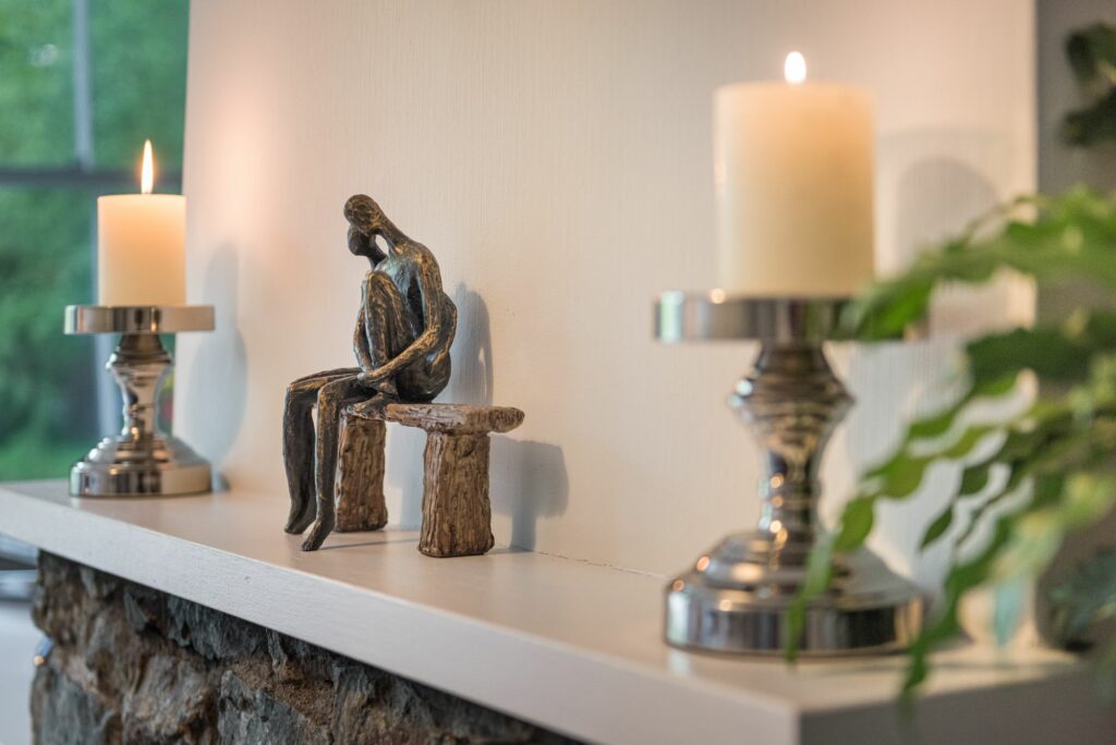 Mantel with candles and decorative statue on it. 