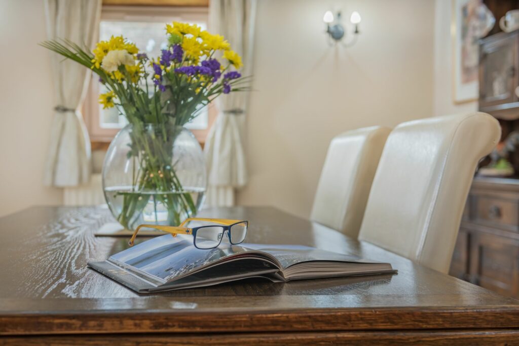 Open book, glasses and vase with flowers on a table. 