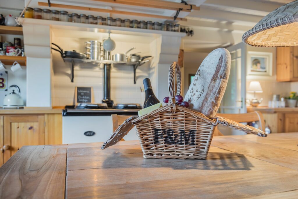 Basket with bread, cheese and wine on a kitchen table. 