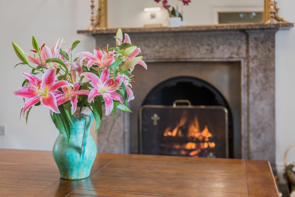 Table with flowers in front of fireplace.