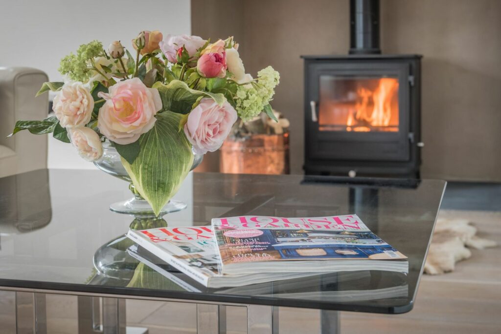 Magazines and vase with flowers on a glass table. 