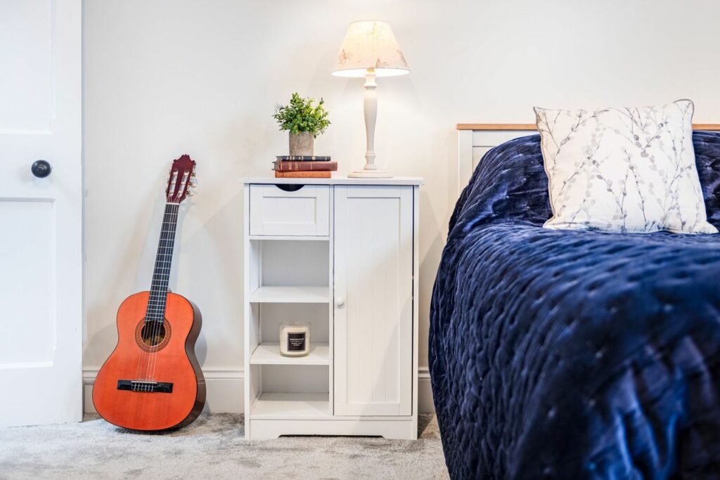 Bedroom in blue and white, and a guitar lying against the wall.