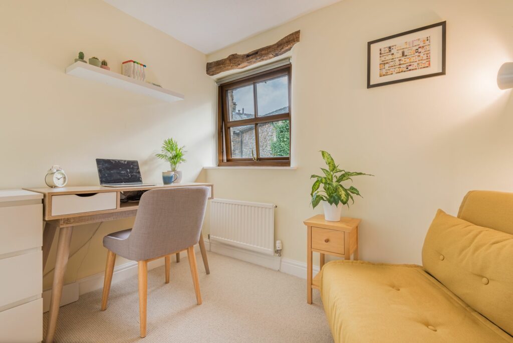 Room corner with desk, chair and small window. 