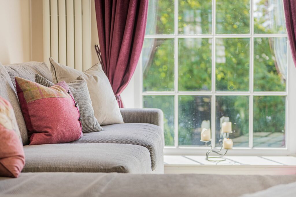 Sofa with cushions in different colors beside a wide window. 