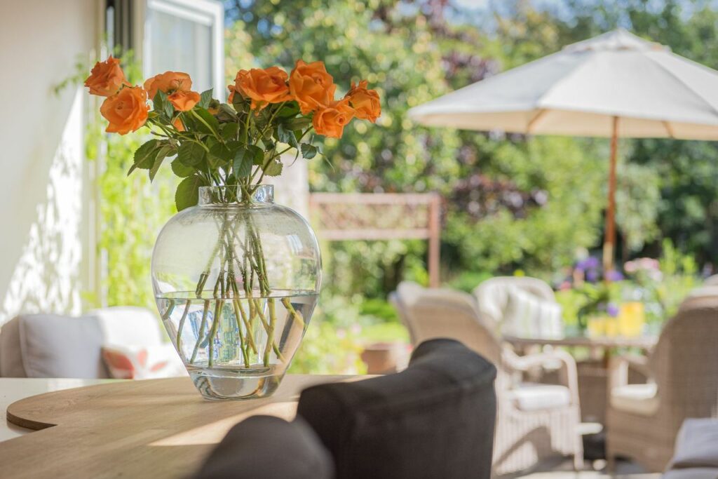 Vase with roses on a table, with view to the garden. 