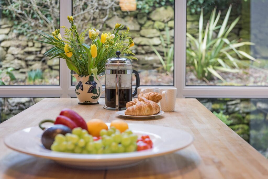 Flowers, French press and fruits on a kitchen table. 