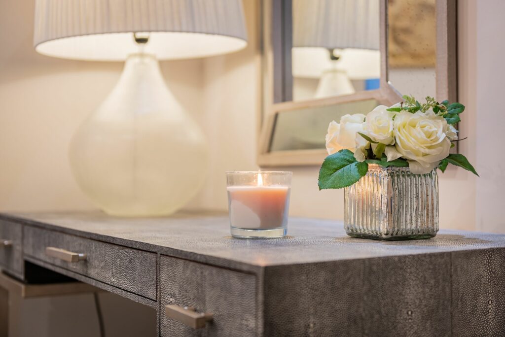 White roses and a candle on a beauty desk. 