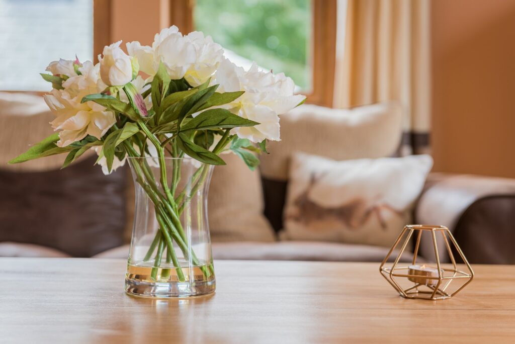 White flowers in a vase on a coffee table.