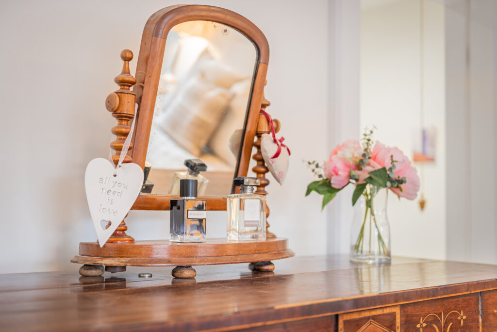 Wooden beauty desk with parfumes and flowers on it 