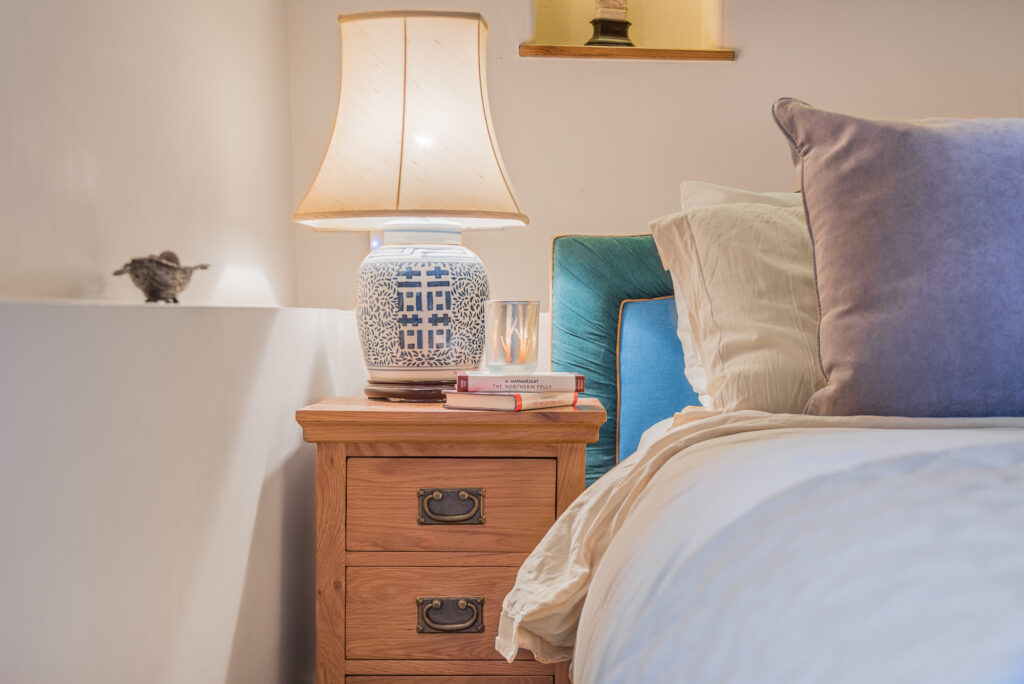 A cozy bedroom corner with nightstand and bed.