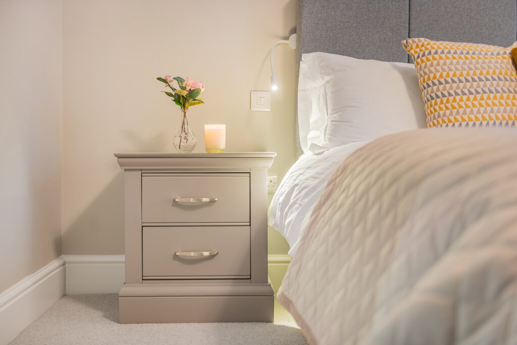 Bedroom corner with nightstand and bed.