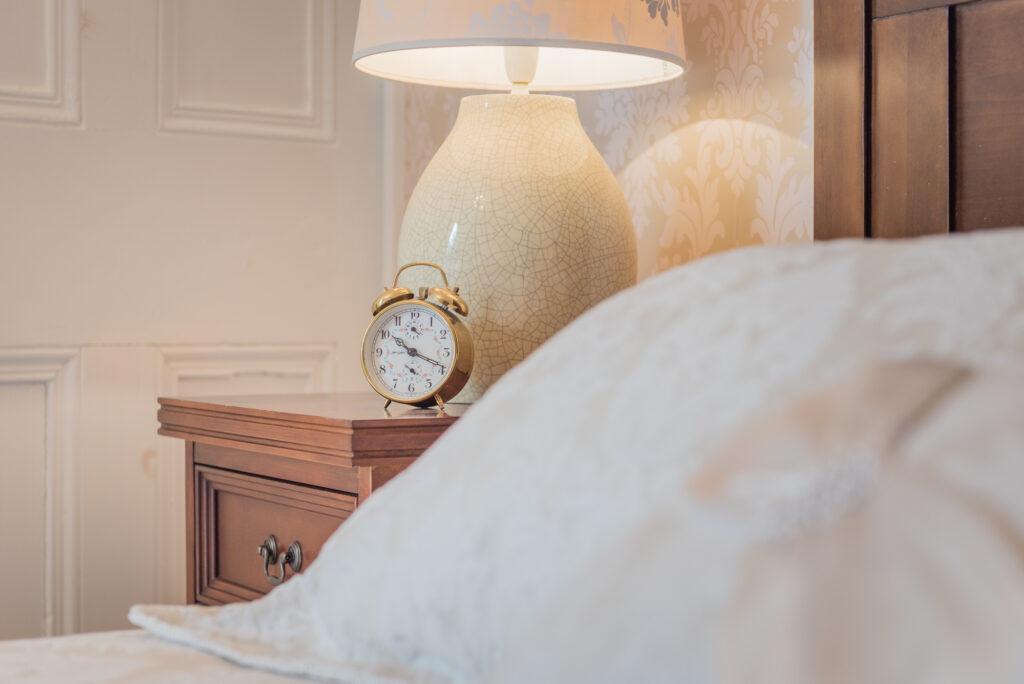 Bedroom corner with bed, night stand and clock on it. 