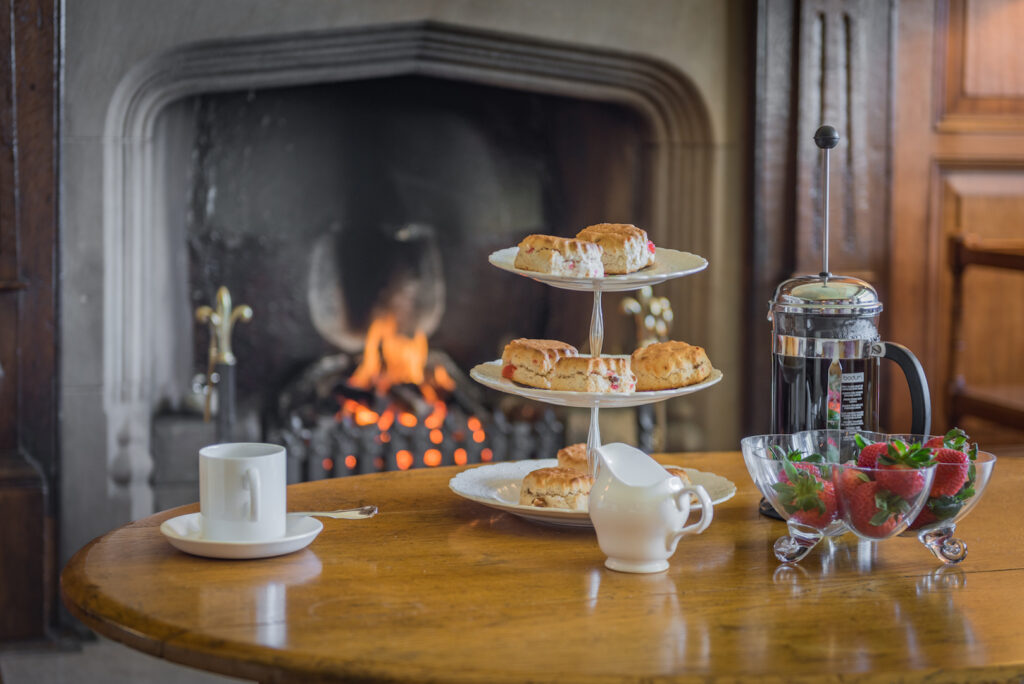 Table in front of a fireplace with desserts, coffee and fruits. 