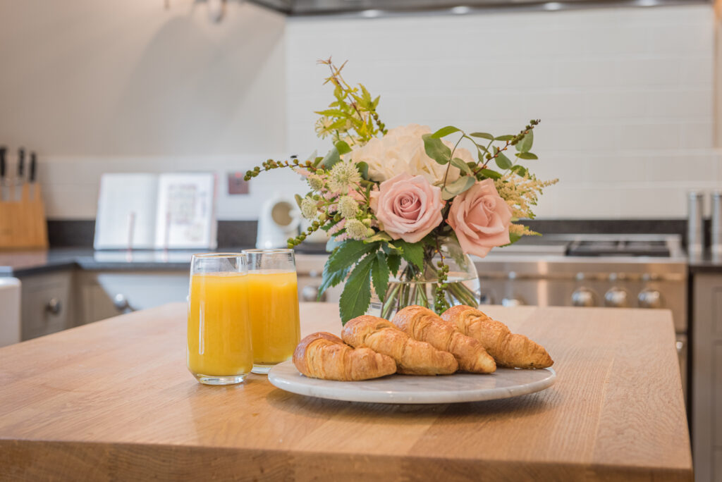 Kitchen table with flowers, croissants and fresh juice on it. 