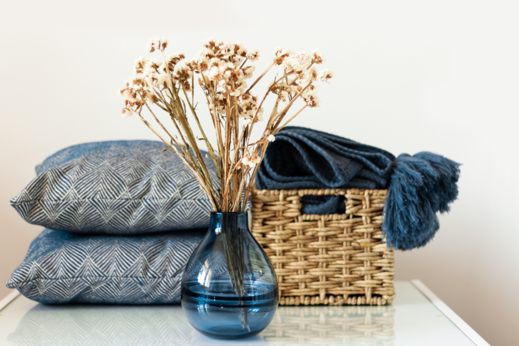 Vase with dried flowers and cushions.