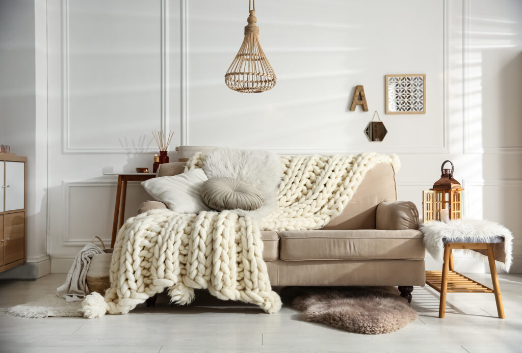 Sofa, arranged with pillows and a blanket, in natural colors.