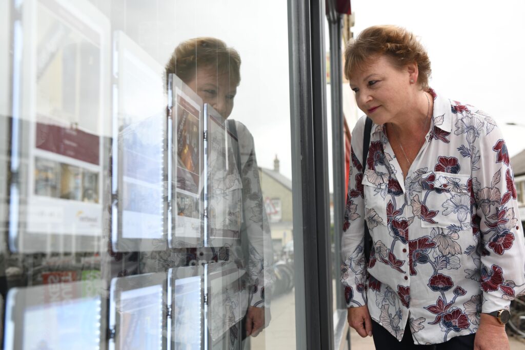 Old lady looking at a real estate storefront