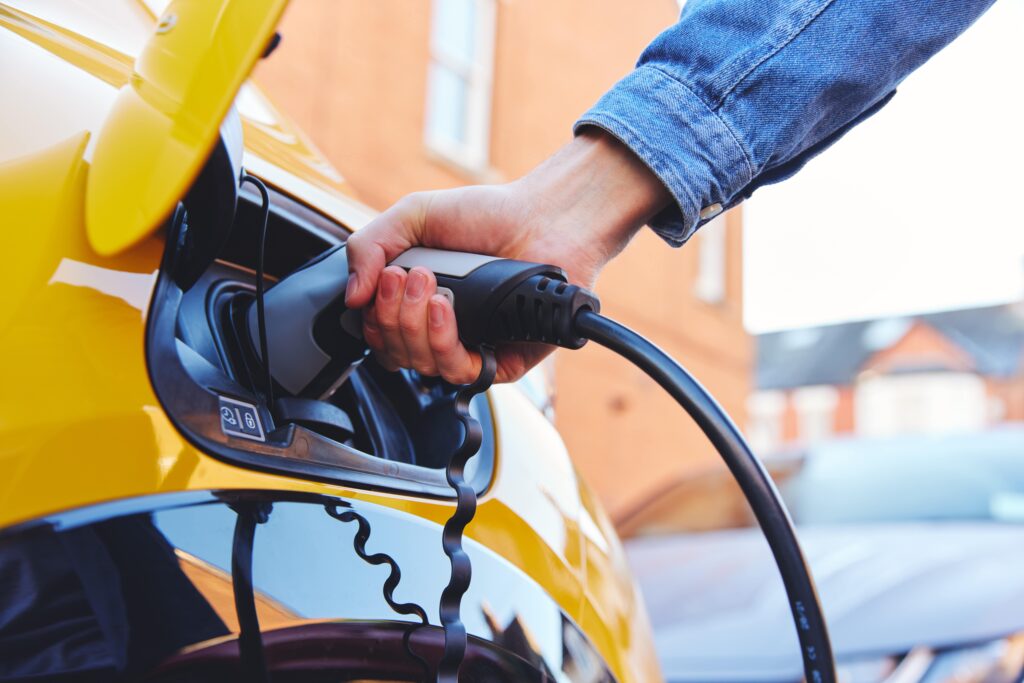 Man charging electric vehicle. 