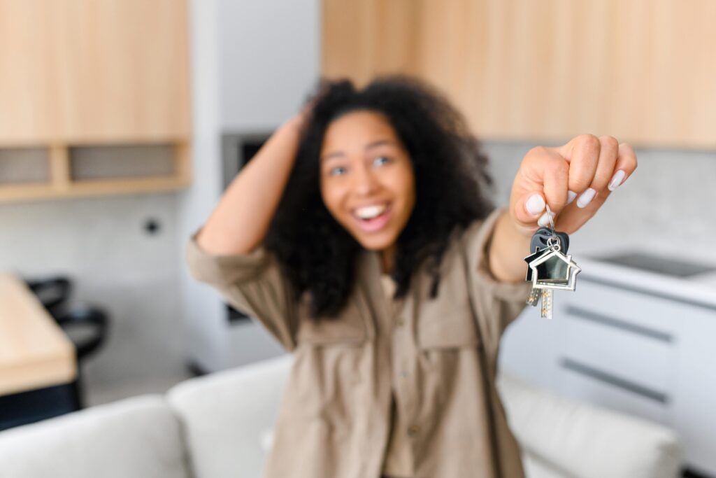 Happy tenant holding a key to her newly rented home. 