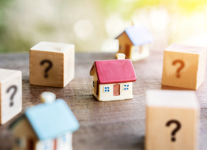 Little house surrounded by cubes with question marks.