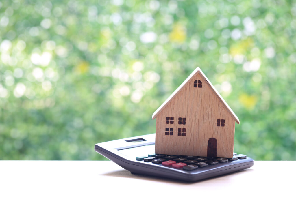 Wooden house on top of a calculator. 