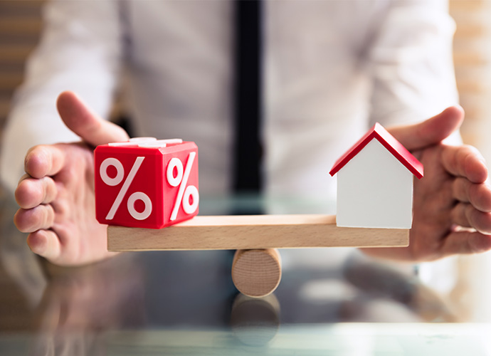 Wooden house and cube with percentage symbol on a scale.