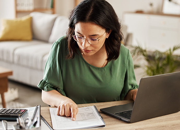 A woman with a notebook and laptop, calculating a budget