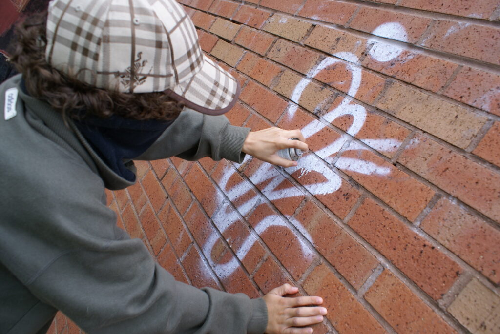 A guy is drawing on a graffiti wall