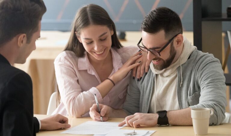 Landlord meeting with a couple at a table as the tenant signs lease extension paperwork, illustrating the process of extending a lease agreement.