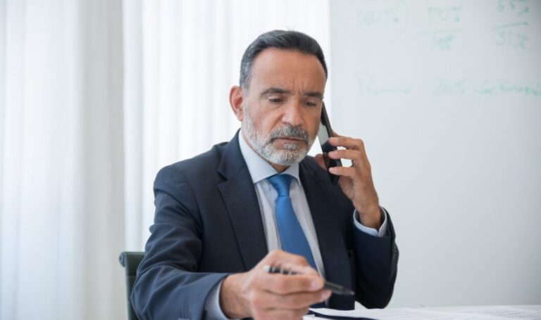 Businessman reviewing documents while on a phone call, illustrating how to conduct a right-to-rent check in a professional setting.