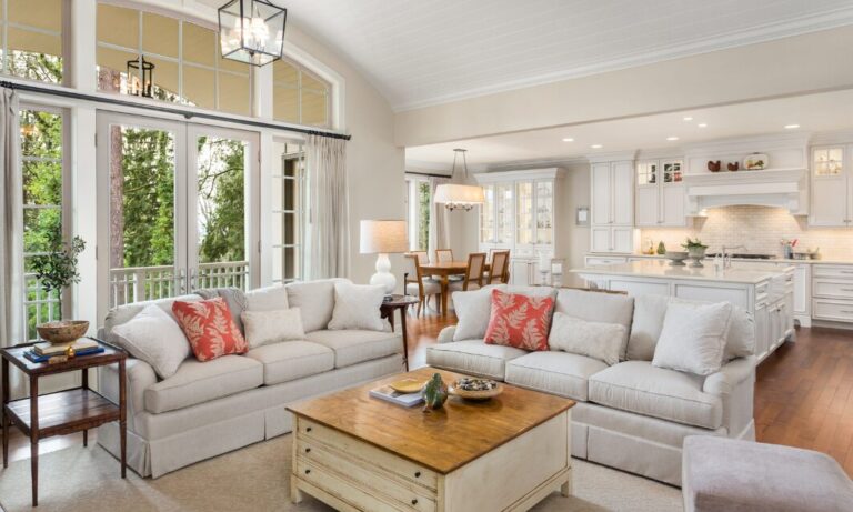 Spacious open-plan living room with large sofas, natural light and a modern white kitchen.
