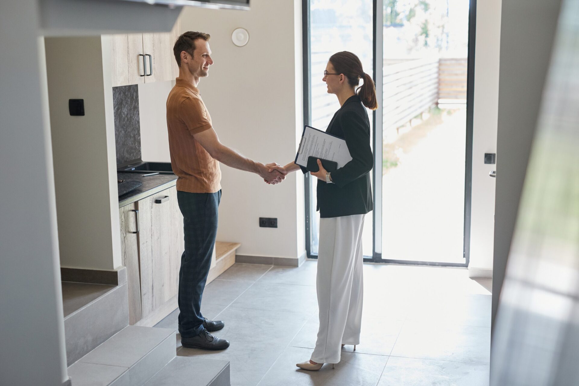 Letting agent shaking hands with a landlord inside a rental property while reviewing paperwork, reflecting preparation for Renters’ Rights Act changes in North Wales