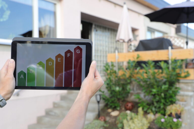 Tablet displaying EPC energy rating scale in front of a residential rental property in Liverpool