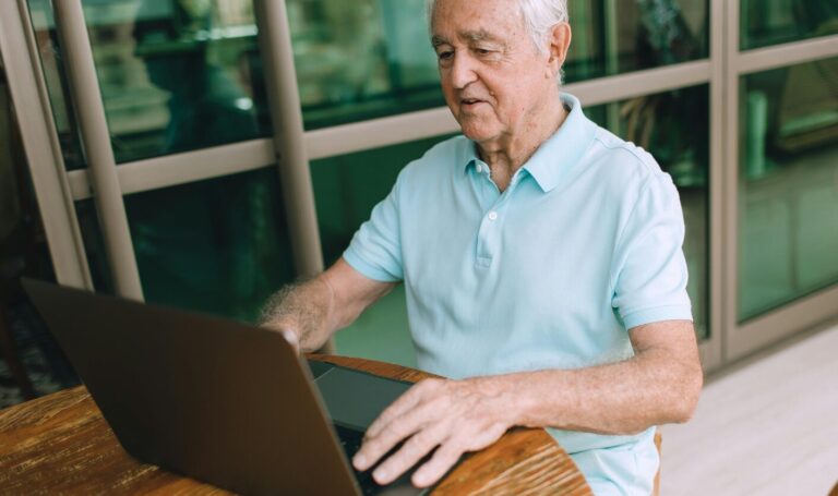 Older landlord using laptop to review tenant applications at home