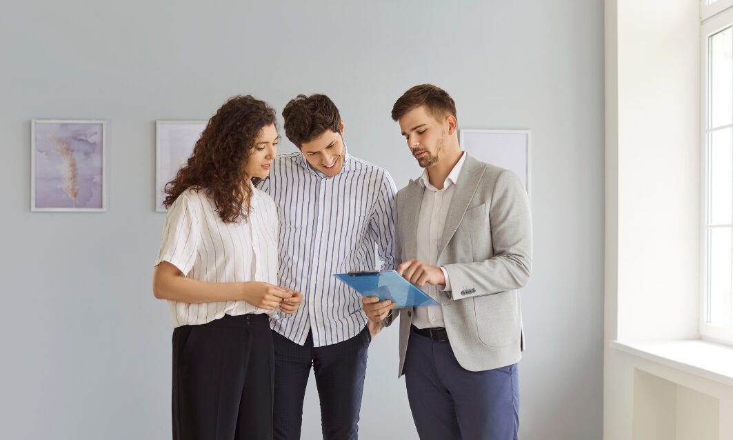 Estate agent showing property details to a couple indoors, representing strong buyer demand and rising house valuations in York