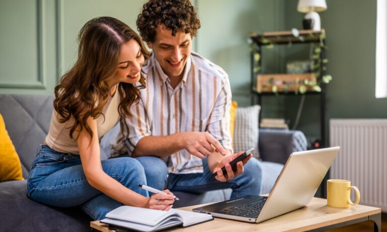 Couple discussing property investment with laptop and notes, representing St Albans rental market opportunities and buy-to-let planning