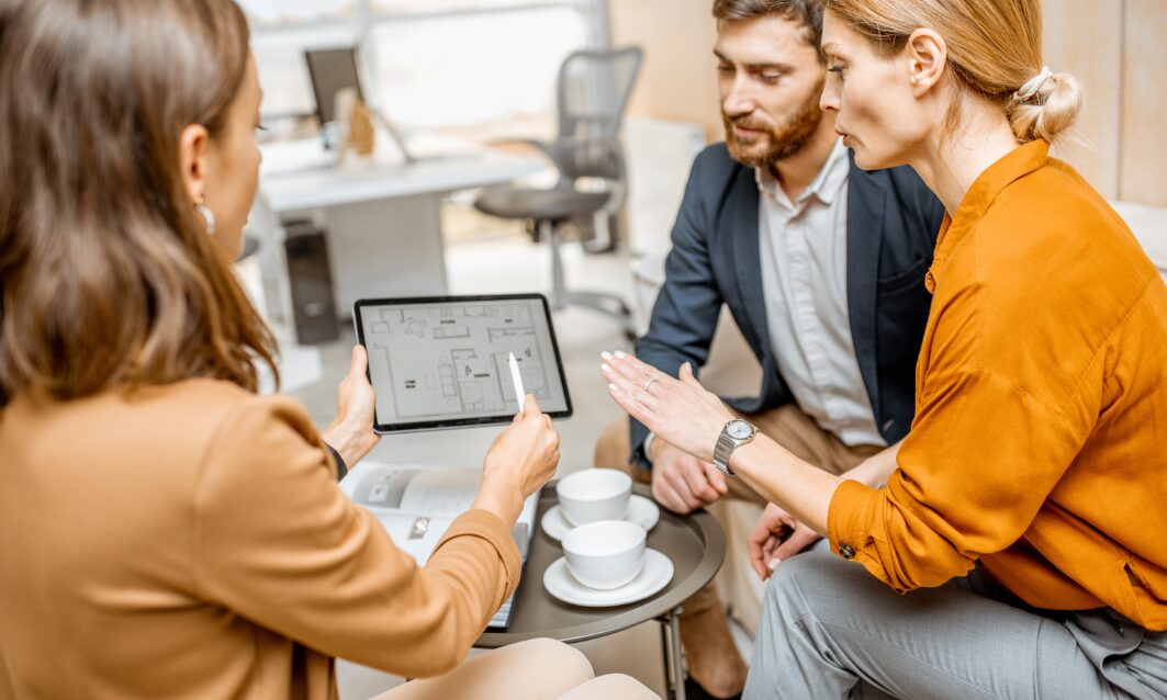 Estate agent showing a property floor plan on a tablet to potential buyers