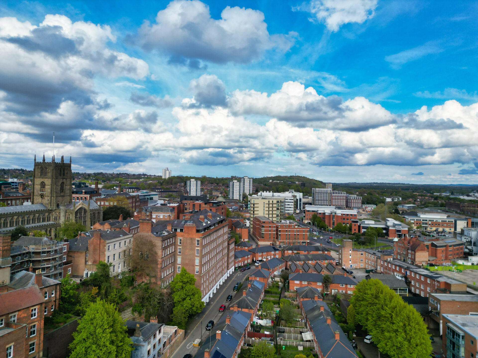 Aerial view of Northampton town centre with residential neighbourhoods, church buildings and urban skyline under dramatic clouds