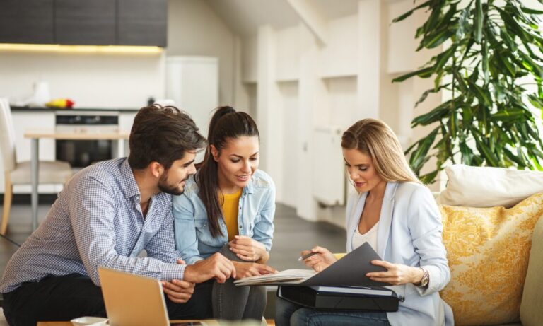 Estate agent discussing property documents with a couple in a modern home, representing St Albans house prices and buyer demand in 2026.