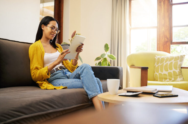 Woman using a tablet while relaxing at home, reflecting buyers researching St Albans property prices and planning their next move.