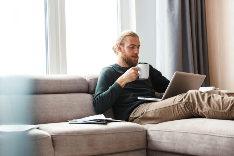 Man using a laptop while relaxing on a sofa, reflecting homeowners researching property values and selling opportunities in Southport after The Open.