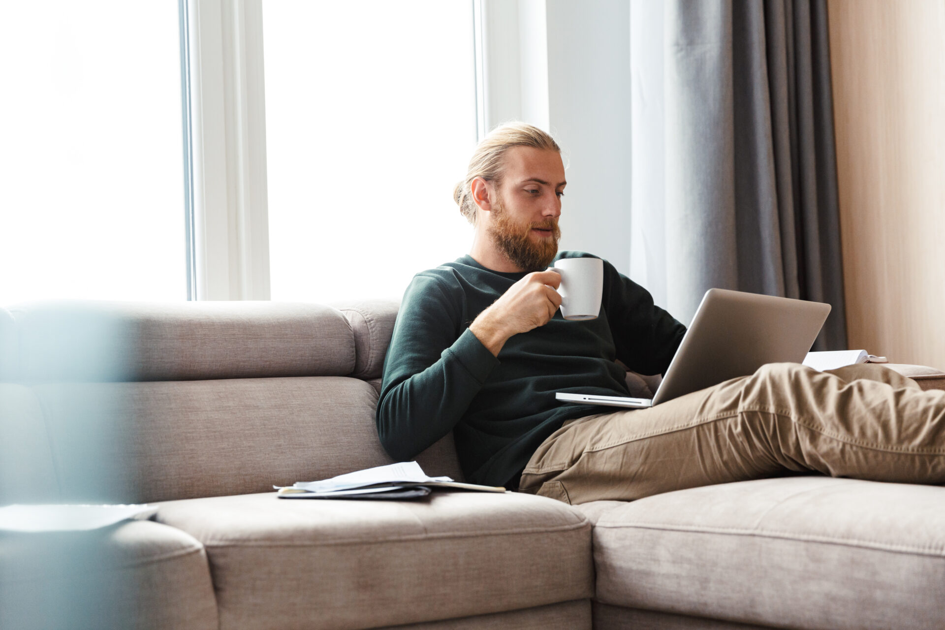 Man using a laptop while relaxing on a sofa, reflecting homeowners researching property values and selling opportunities in Southport after The Open.
