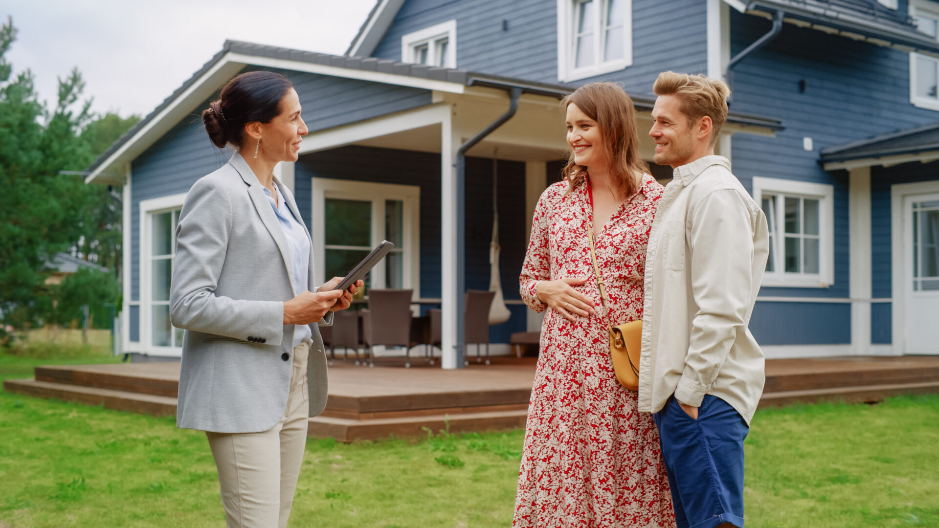 Estate agent speaking with a couple outside a modern home, reflecting property selling advice and buyer demand for new builds and family homes in Warminster.