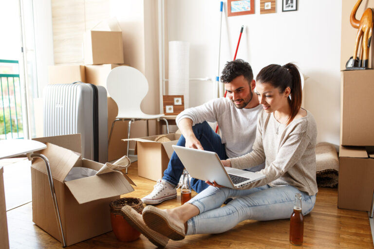 Couple using a laptop while unpacking moving boxes in a rental home, reflecting tenant changes, rental management and landlord responsibilities under the Renters’ Rights Act in York.