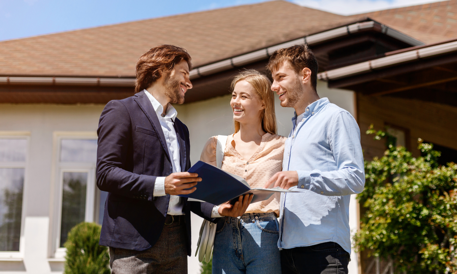 Couple discussing a property purchase with an estate agent outside a home