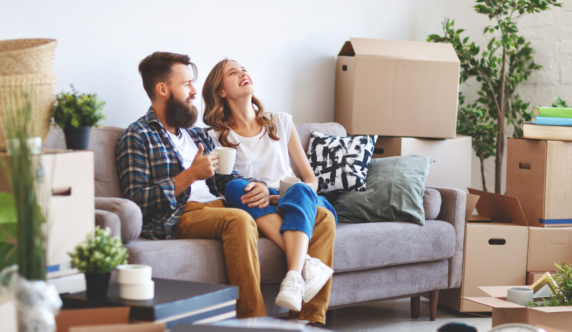 Couple relaxing in a living room surrounded by moving boxes after switching to a long-term rental property.