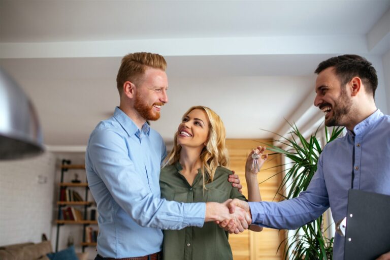 Estate agent handing keys to smiling home buyers